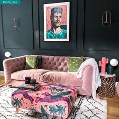 a living room with a pink couch and ottoman in front of black walls, an art work on the wall