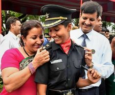 two people standing next to each other and one is holding something in his hand while the other woman holds another person's arm