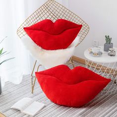 two red lips shaped pillows sitting on top of a white table next to a chair