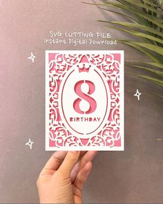 someone is holding up a birthday card with the number 8 on it, in front of a plant