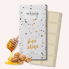 a bar of milk chocolate next to some nuts and honey on a white background with gold confetti