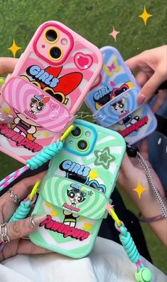 four cell phones with cartoon characters on them are being held by two people in the grass