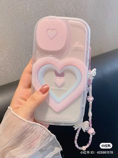 a hand holding a phone case with two heart shaped magnets attached to the back