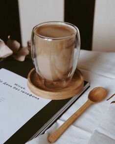 a cup of coffee sitting on top of a table next to a spoon and paper