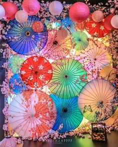 there are many colorful umbrellas hanging on the wall