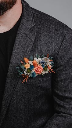 a man in a suit with flowers on his lapel and a black t - shirt