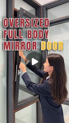 a woman in business attire is opening a glass door with the words oversized full body mirror door