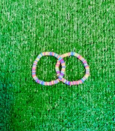 two colorful bracelets laying on top of green grass