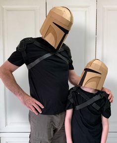 a man and child wearing cardboard helmets standing next to each other