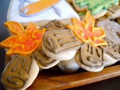 decorated cookies on a wooden platter with frosting and icing leaves in the shape of flowers