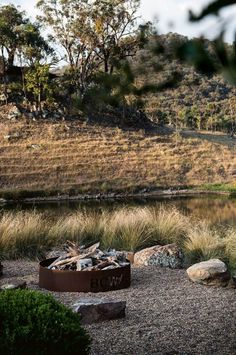 an outdoor fire pit surrounded by rocks and grass