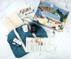 an open box containing various items from the causebox on a marble countertop next to a blue bag