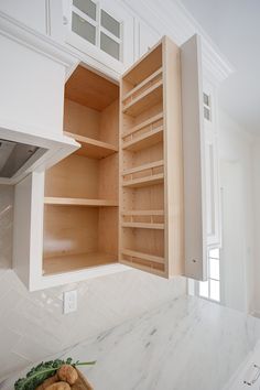 an open cabinet in the middle of a kitchen