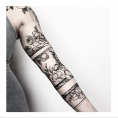 a woman's arm with tattoos and flowers on the side of her arm, in black and white