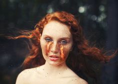 a woman with freckles on her face and red hair is posing for the camera