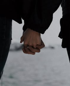 two people holding hands while standing next to each other on top of snow covered ground