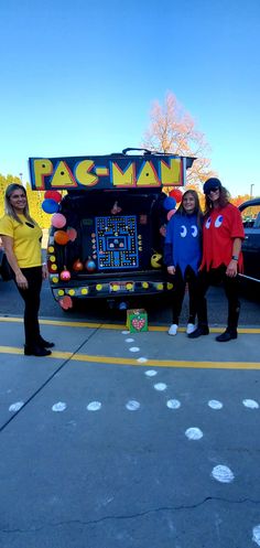 three people standing in front of a pac - man truck with an arcade game on it