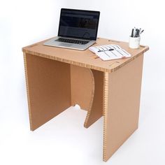 a laptop computer sitting on top of a wooden desk next to a pen and paper