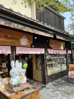 a store front with an easter bunny statue in the foreground and other items on display outside