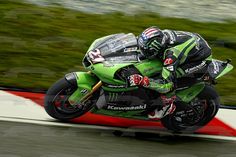 a person riding a motorcycle on a track with grass in the backgrouund