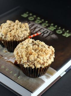 two muffins sitting on top of a book with crumbs on them