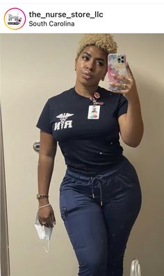 a woman taking a selfie with her cell phone in front of the mirror while wearing blue pants