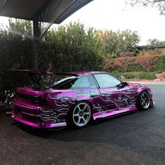 a purple car with flames painted on it's hood parked in a parking lot