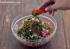 a glass bowl filled with chopped vegetables on top of a wooden table