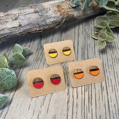 three pairs of earrings sitting on top of a wooden table next to succulents