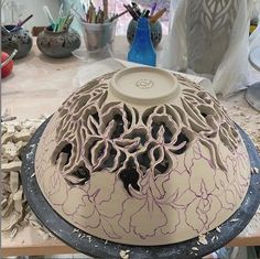 a large white vase sitting on top of a wooden table covered in lots of crafting supplies