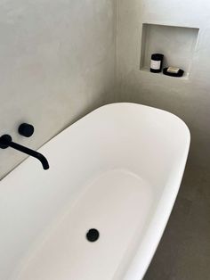 a white bath tub sitting in a bathroom next to a shelf with candles on it