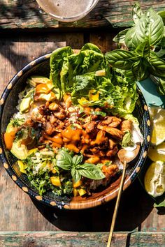 a bowl filled with meat and vegetables on top of a wooden table next to sliced limes