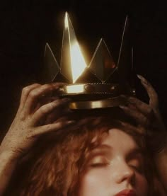 a woman is holding up a lit candle to her head while wearing a tiara