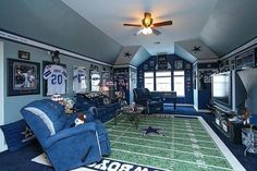 a football themed living room with blue couches and green carpeted area rugs