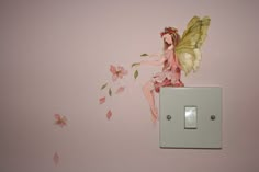 a little fairy sitting on top of a light switch in a pink room with flowers painted on the walls