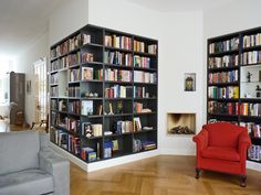 a red chair sitting in front of a book shelf filled with books