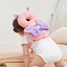 a small child is playing with a stuffed toy in the shape of a butterfly on her back