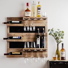 wine glasses and bottles are sitting on a wooden pallet mounted to the side of a wall