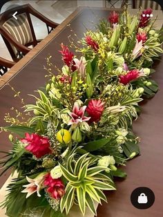 a long table with flowers and greenery sitting on it's side by itself