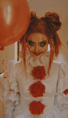 a woman with red hair and makeup is holding balloons in front of her face as she looks at the camera