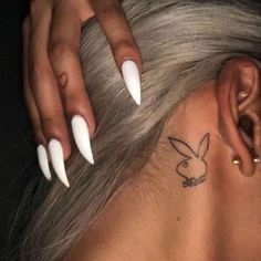 a woman with white nails and a tattoo behind her ear