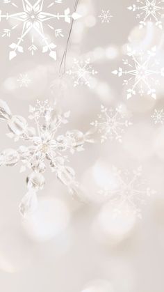 a snowflake is hanging from a string on a white background with blurry lights