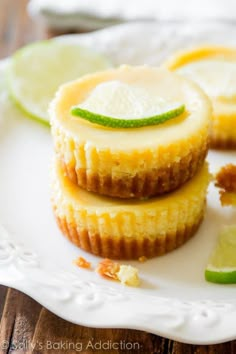 three lemon custard tarts on a white plate with lime wedges next to them