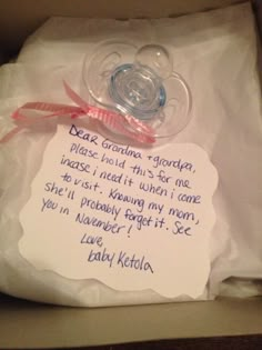 a baby pacifier in a box with a note attached to the end of it