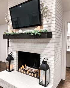 a white brick fireplace with candles and a flat screen tv mounted above the mantel