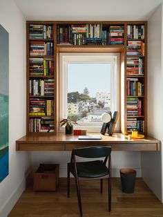 a desk with a chair and bookshelf in front of a window filled with books