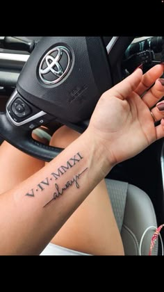 a woman driving a car with a tattoo on her arm that reads, viv vmxy bling