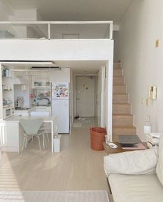 a living room filled with furniture next to a white kitchen and dining room table on top of a hard wood floor