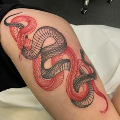 a red and black snake tattoo on the arm