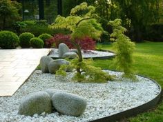 a garden with rocks and trees in the center, surrounded by green grass on either side